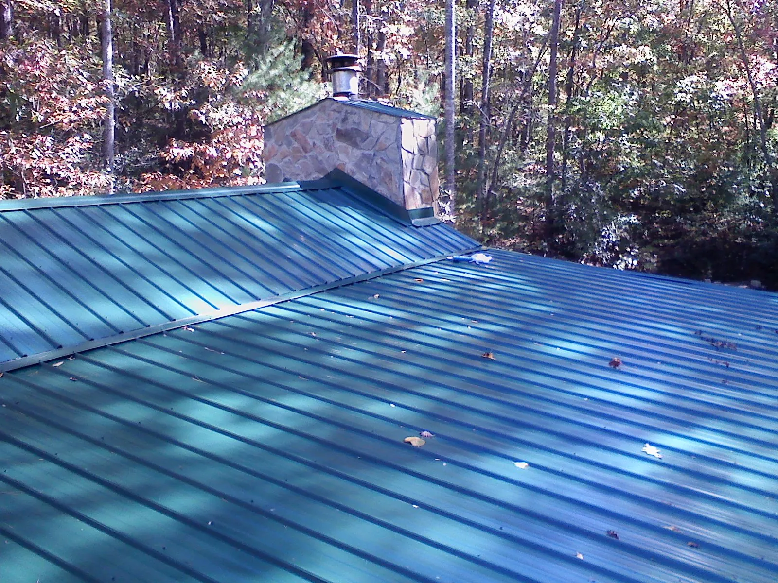 New green metal roof and stone chimney surrounded by autumn woods in Stanhope