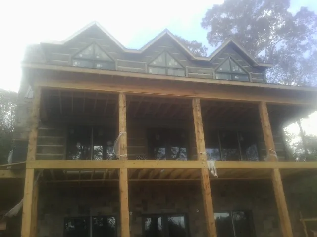 Dormers and porch framing on a large log home under construction — Roof Coating work by our crew in Stanhope