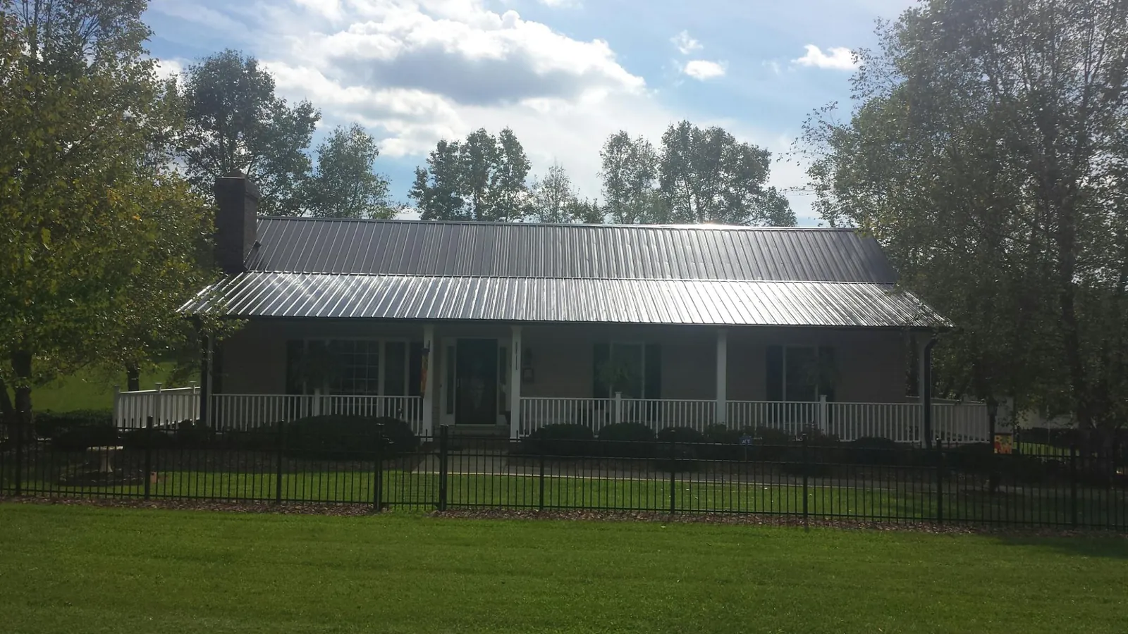 Gray metal roof on a brick ranch with a full width front porch — Gutter Guard Installation work by our crew in Stanhope