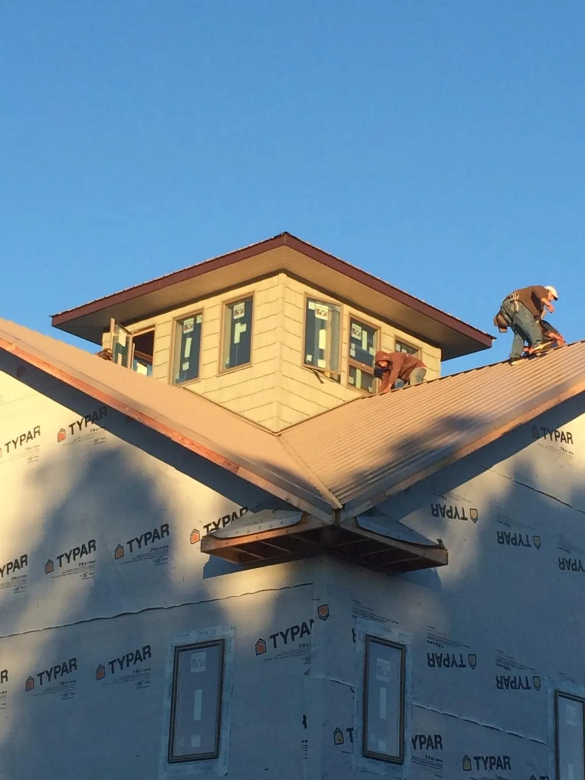 Roofers working around a rooftop cupola on a new metal roof at sunset — Roof Waterproofing in Stanhope by Roofing Brothers